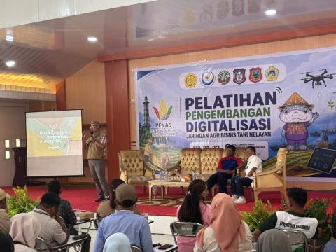 Peserta pelatihan digitalisasi duduk menghadap panggung dan layar proyektor di aula