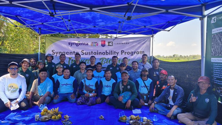 Foto kelompok peserta acara “Sustainability Program” duduk di bawah tenda biru.