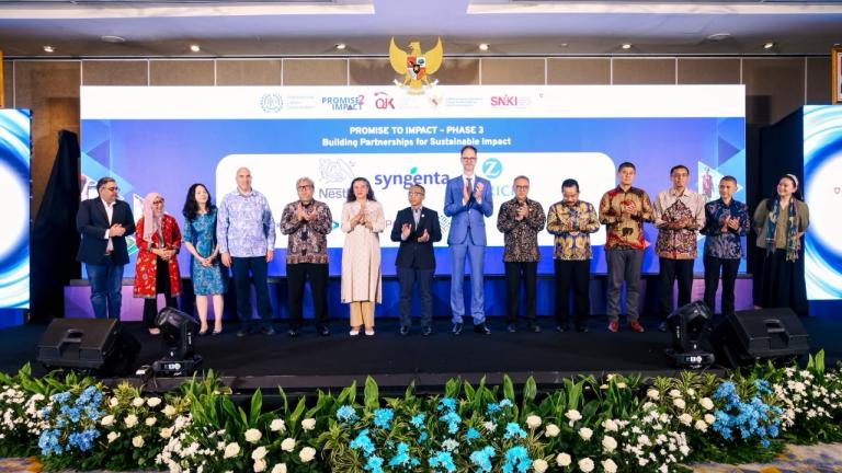 Foto bersama para pejabat dan peserta di panggung acara, dekorasi bunga di depan.