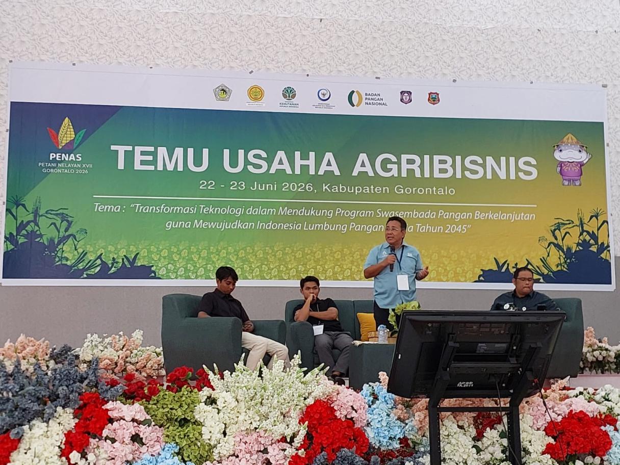 Spanduk “Temu Usaha Agribisnis” di panggung, tiga pria duduk di depan dekorasi bunga merah-putih