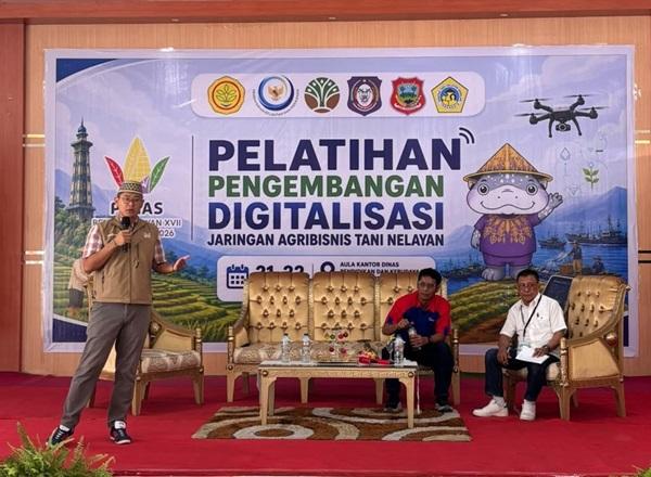 Spanduk pelatihan digitalisasi; pembicara berdiri, dua peserta duduk di panggung merah
