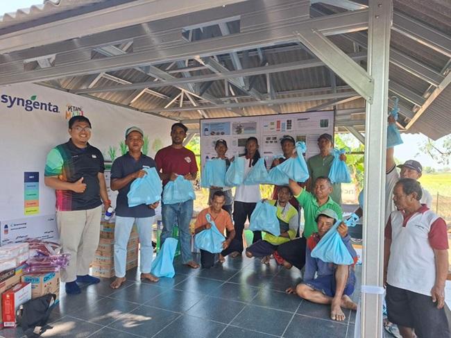 Sekelompok orang berpose di dalam aula terbuka, memegang tas dan sertifikat.